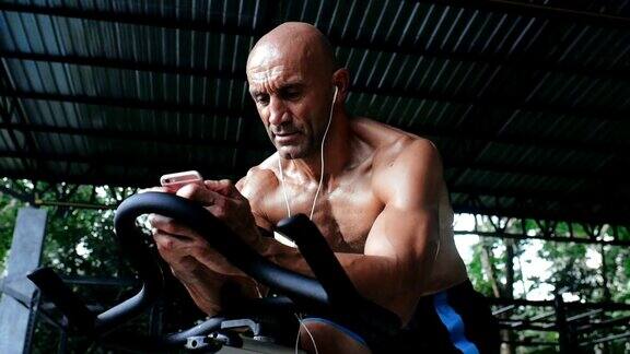 男人在健身自行车上训练用手机app记录运动成就