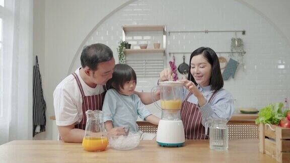 亚洲家庭爸爸妈妈和儿子帮忙做饭在厨房做冰沙