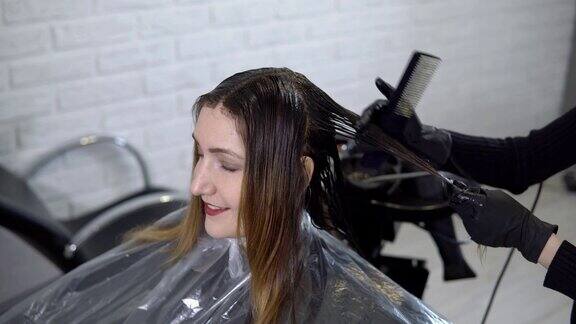 美容院里发型师给一位年轻女子做头发