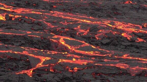 冰岛火山喷发大自然的奇迹炽热的熔岩从地面喷发出来无人机在活跃的火山口上空飞行熔岩穿过深色岩石表面凝固开裂