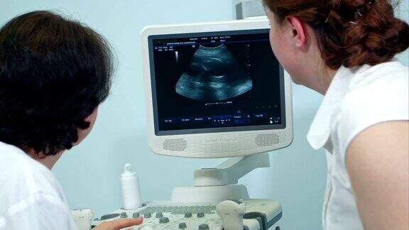 妇科医生和孕妇在看胎儿的超声波图