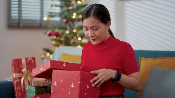 一名亚洲女子在圣诞节打开礼盒时惊喜不已
