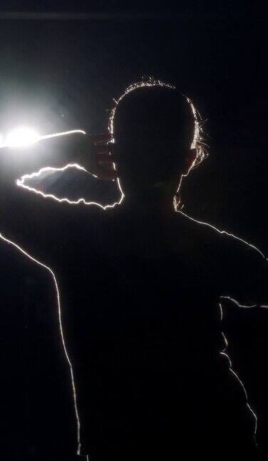 垂直视频的年轻女舞者表演嘻哈舞蹈在慢动作与光和烟的背景