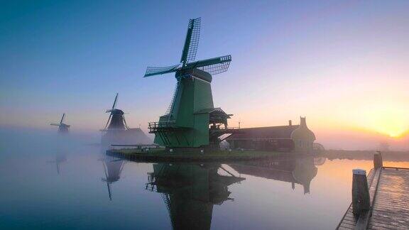 荷兰传统的风车在日出时的薄雾中沿着ZaanseSchans运河在荷兰