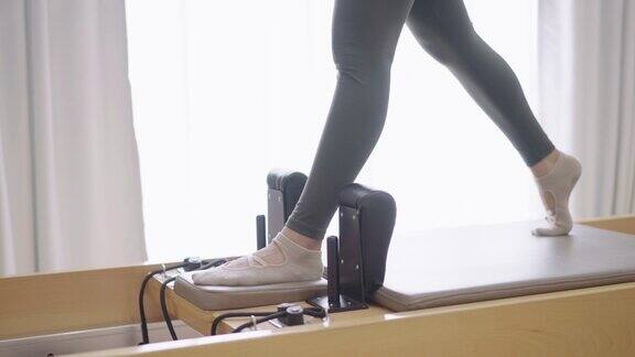 低角度拍摄的健康女性腿站在普拉提改造机的机动