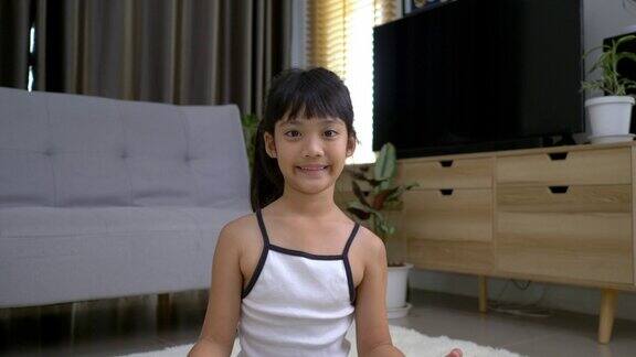 亚洲可爱的女孩坐在地毯上冥想的姿势