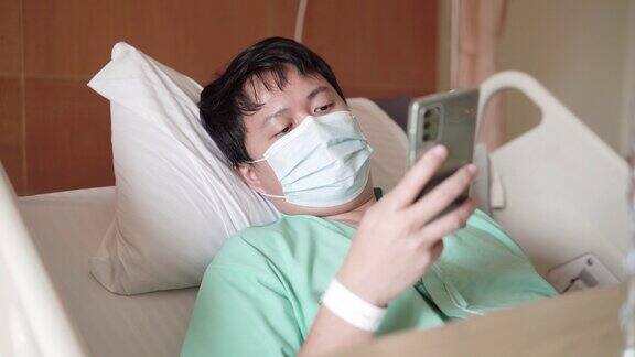 男性亚洲病人在医院病房使用手机