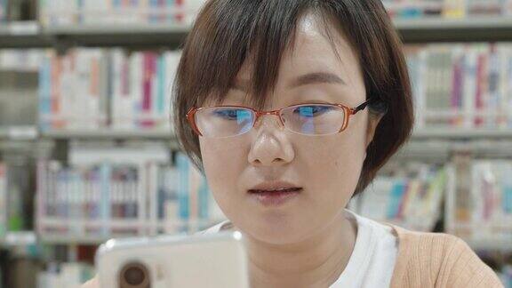 亚洲女人在图书馆用智能手机