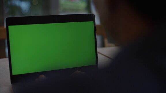 在咖啡馆用绿屏笔记本电脑的男人