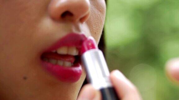 特写亚洲女人的嘴唇化妆美丽的女孩正在涂唇彩