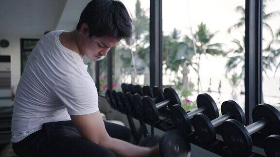 图为一名亚洲男子上午在度假村健身中心进行哑铃重量训练