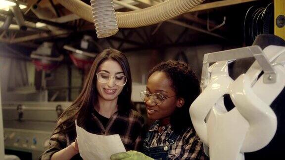 两个年轻的女性设计师工作在动力外骨骼项目在木材车间