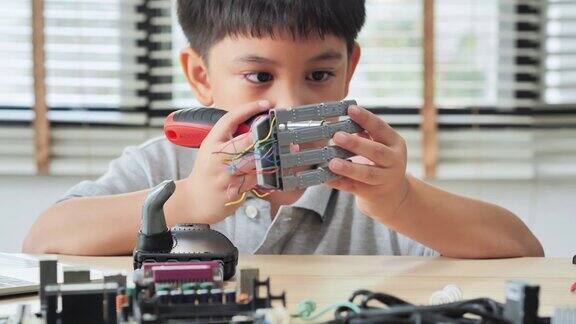 男孩在家里用电脑制作和编程并制作一个机器人手臂作为学校的科学项目他对自己的工作非常满意教育、儿童、技术、科学是人们的理念