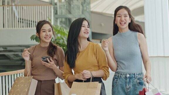 一群年轻的亚洲女人拿着购物袋在百货公司购物朋友们周末在购物中心散步聊天