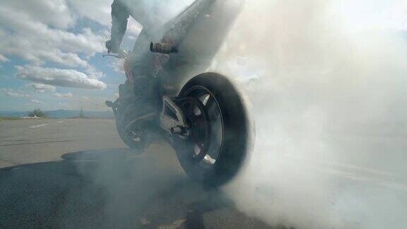 一个摩托车车轮燃烧橡胶的特写一辆运动摩托车的车轮下冒出了烟雾和火花