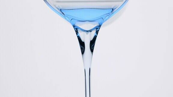 蓝色的唐茜油正从烧杯倒在灰色的背景上