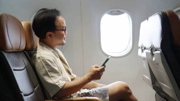 4K亚洲男子乘客在飞机上使用手机