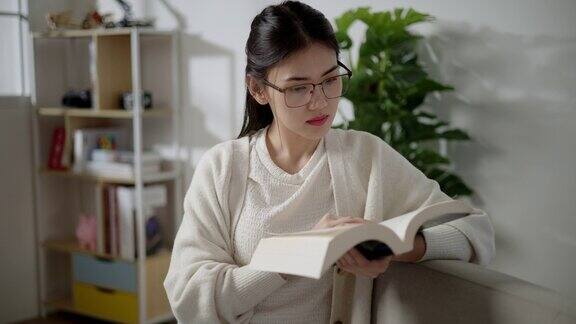 亚洲年轻女子在家里的客厅读教科书