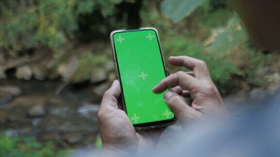 近距离男子持有智能手机与绿色屏幕