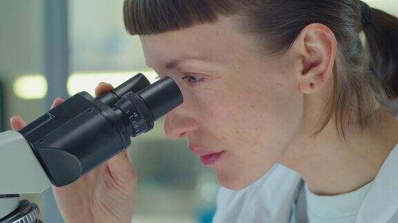 用显微镜做实验室研究的女科学家