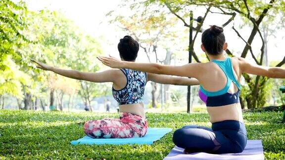 两个年轻女人在早上的公园里做瑜伽