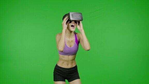 健康女性在绿色屏幕上的VR头盔中环顾四周非常惊讶和震惊色度键技术增强现实亚洲妇女用于图形覆盖和剪切的目的