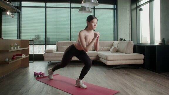 运动的亚洲妇女在运动服工作在家年轻迷人的女性在客厅的红色健身垫上健身在家里进行保健和运动心理治疗
