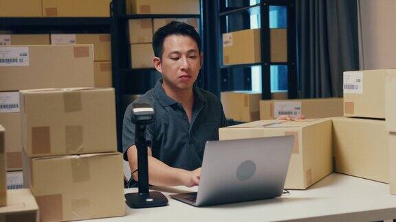 亚洲商人使用条码机扫描纸盒中的客户数据并在笔记本电脑上输入注册在线信息订单明细以便在仓库发送快递