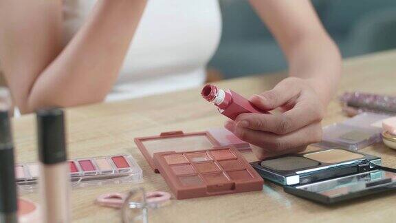 女性的手拿着唇彩在梳妆台上在家里用它化妆
