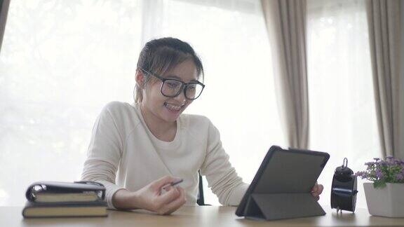 年轻女性在家用电子平板电脑工作