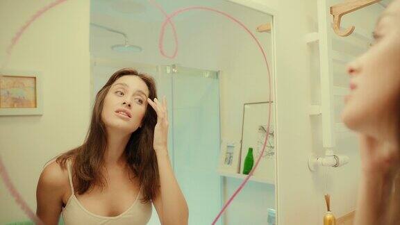 迷人的黑发享受她的倒影在镜子上画红心早上浴室常规