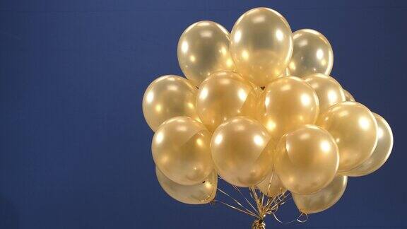 装饰元素金色气球在视频中旋转作为节日的惊喜:在蓝色背景下情人节、生日、圣诞节或新年