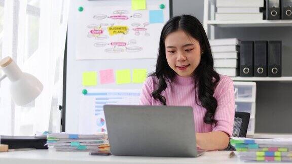 亚洲女性在办公室用笔记本电脑处理文书工作
