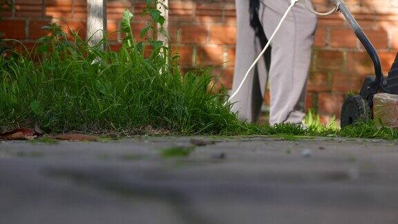 前视图:在家里使用割草机的人割草机修剪草坪打扫花园使用电动割草机的人