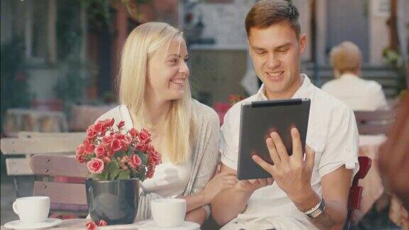 年轻的微笑情侣在咖啡店使用平板电脑