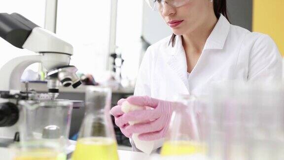 年轻的女科学家用餐巾擦拭桌子和显微镜
