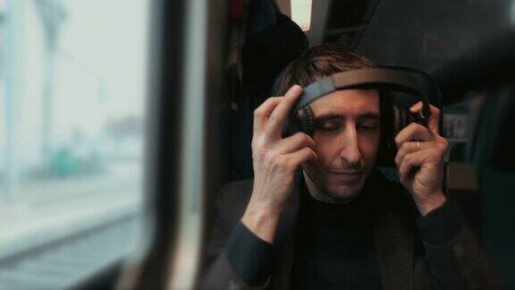 乘客在乘坐火车时摘掉耳机望向窗外