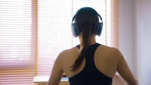 女人穿着运动布在家里锻炼在笔记本电脑屏幕上观看和跟随教练