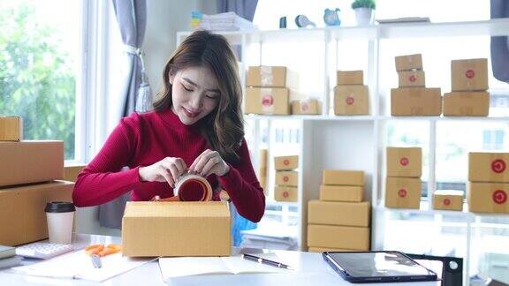 在家中工作的亚洲妇女在小企业检查在线订单准备将盒装物品送到客户手中