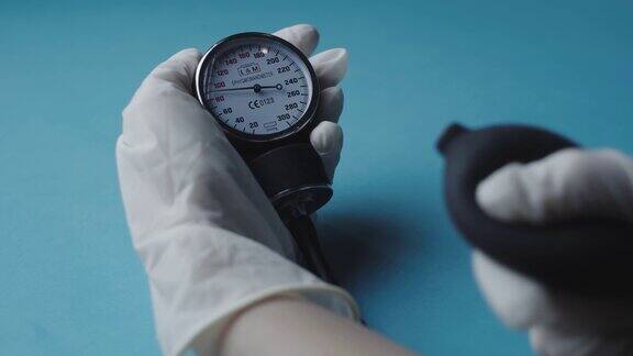 戴着手套的手用老式血压计测量血压的特写