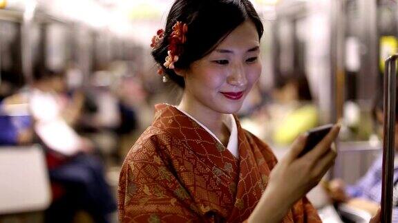 穿着和服的日本女孩在地铁里给她的朋友发短信