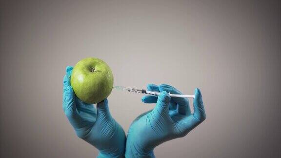 女性双手在医用手套中制作注射苹果健康和不健康的饮食转基因产品化学