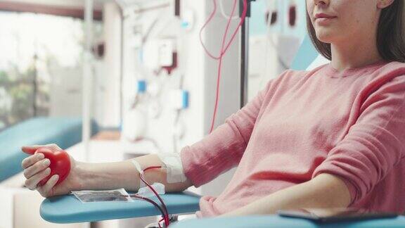 医院女献血者带导管的手部特写镜头镜头从手掌挤压心形红球到将血液泵到白人妇女的脸上为烧伤受害者捐款