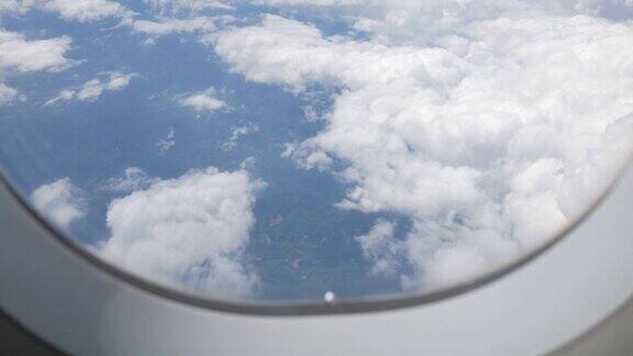 透过飞机的窗户看蓝天和白色蓬松的云从飞机飞行飞越云在一个晴朗的日子与云移动在夏天