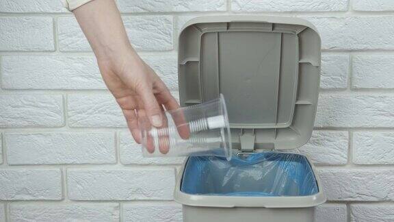 把一次性塑料杯扔进垃圾桶