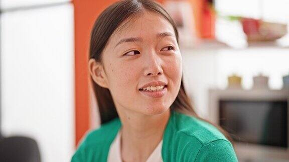 年轻的中国女子微笑着自信地坐在餐厅的桌子上