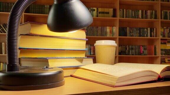 图书馆书桌上的书、咖啡和旋转的台灯黑暗房间里的书架