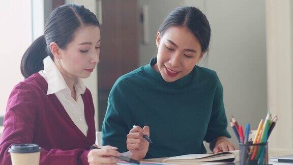 亚洲年轻有创造力的人日本女老板主管教学实习生或新员工西班牙裔女孩在现代办公室帮助解决困难的任务