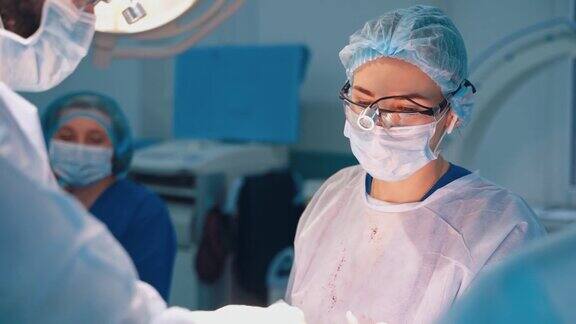 手术的进展穿着医疗制服的专业外科医生进行整形手术女助理帮助医生