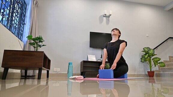 有吸引力的年轻亚洲女人锻炼和坐在瑜伽的位置而休息在家里